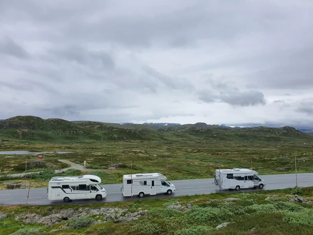 Trzy kampery na górskiej drodze Kolumna trzech kamperów zaparkowanych przy drodze wśród zielonych wzgórz
