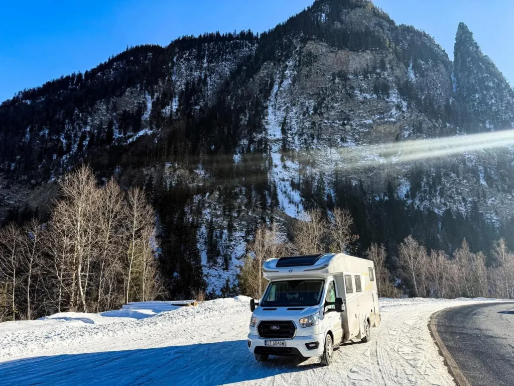 Kamper Roller Team Zefiro zaparkowany przy ośnieżonej drodze z widokiem na górski krajobraz zimą.