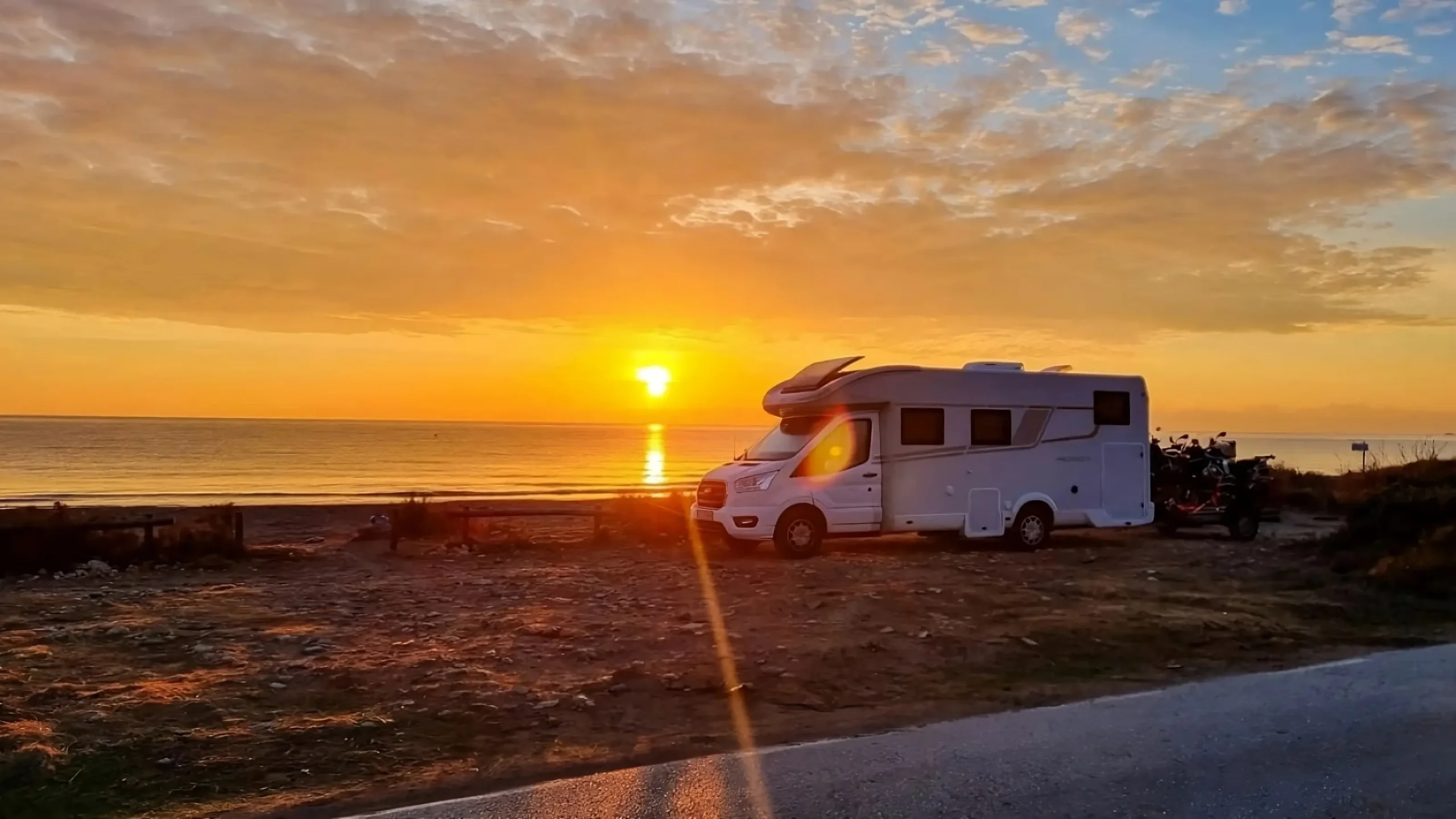 Kamper nad morzem o zachodzie słońca Kamper zaparkowany przy plaży o zachodzie słońca, idealne miejsce na nocleg w podróży